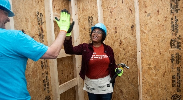 Habitat homeowner high-fiving a volunteer on a build site.